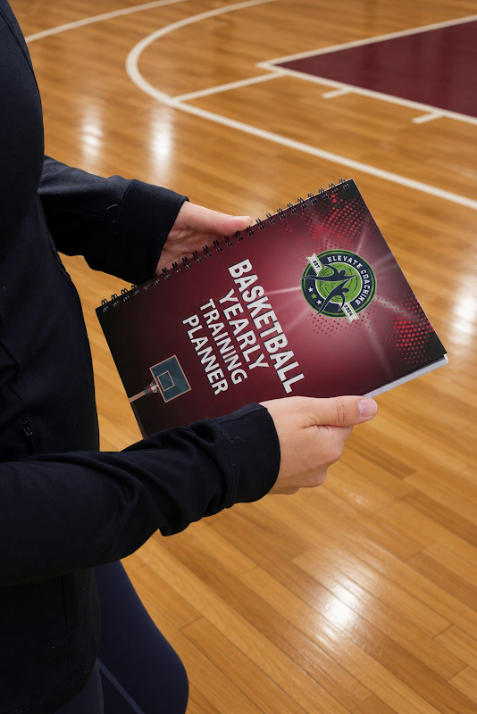 Person holding a 'Basketball Yearly Training Planner' on a basketball court